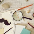 Father`s tools, black paper mustache, magnifying glass, pencils and a greeting inscription in a notebook on a light wooden table