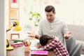 Father scolding his daughter while helping with homework at table