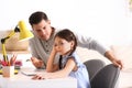 Father scolding his daughter while helping with homework at table