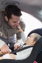 Father securing baby in the car seat Royalty Free Stock Photo