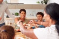 Father Serving As Multi-Generation Mixed Race Family Eat Meal Around Table At Home Together Royalty Free Stock Photo
