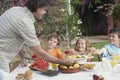 Father Serving Pineapple Slices To Kids At Outdoor Table