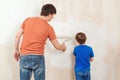 Father showing his son how painting wall with a roller Royalty Free Stock Photo