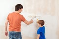 Father showing his son how painting wall with a roller Royalty Free Stock Photo