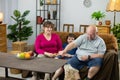 The father shows the grape to the dog and the whole family smiles.