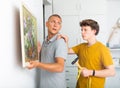 Father shows his son how to hang painting on the wall of house Royalty Free Stock Photo