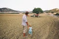 Father shows his toddler son an old tractor on a plowed field among hills. Countryside in Cyprus