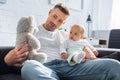 father sitting on couch with adorable baby daughter and playing with teddy bear Royalty Free Stock Photo