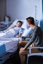 Father sitting beside her daughter lying on a hospital bed Royalty Free Stock Photo