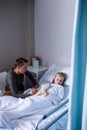 Father sitting beside her daughter lying on a hospital bed Royalty Free Stock Photo