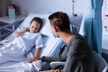 Father sitting beside her daughter lying on a hospital bed Royalty Free Stock Photo