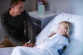 Father sitting beside her daughter lying on a hospital bed Royalty Free Stock Photo