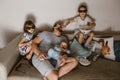 Father is sitting on the sofa with baby on his arms and his two daughters in the special glasses watching tv and eating Royalty Free Stock Photo