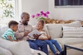 Father Sitting On Sofa With Children At Home Reading Book Together Royalty Free Stock Photo