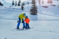 Father in skiing school glide backwards teach child to ski