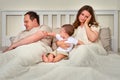 Father sleeps while mother takes care of baby boy, parents and infant c Royalty Free Stock Photo