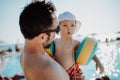 Father with small child with armbands standing by swimming pool on summer holiday. Royalty Free Stock Photo