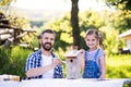 Father with a small daughter outside, painting wooden birdhouse.