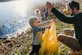 Father with small kids collecting rubbish outdoors in nature, plogging concept.