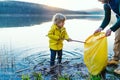 Father with small son collecting rubbish outdoors in nature, plogging concept.