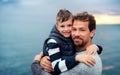 Father with small son on a walk outdoors standing on beach at dusk. Royalty Free Stock Photo