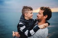 Father with small son on a walk outdoors standing on beach at dusk. Royalty Free Stock Photo