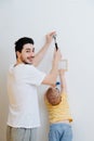 Father with a small toddler son are attaching framed drawing to the wall