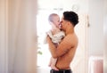 Father and small toddler son wrapped in towel in a bathroom indoors at home.