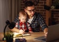 Father and son baby work at home at computer in dark Royalty Free Stock Photo