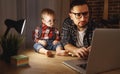 Father and son baby work at home at computer in dark Royalty Free Stock Photo