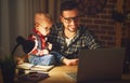 Father and son baby work at home at computer in dark Royalty Free Stock Photo