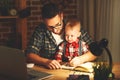 Father and son baby work at home at computer in dark Royalty Free Stock Photo