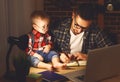 Father and son baby work at home at computer in dark Royalty Free Stock Photo