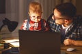 Father and son baby work at home at computer in dark Royalty Free Stock Photo