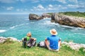Father and son backpacker travelers rest on the rocky sea side a