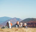 Father and son backpackers hikers rest on mountain hill with their beagle dog