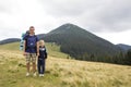 Father and son with backpacks hiking together in summer mountains. Dad and child holding hands on landscape mountain view. Active Royalty Free Stock Photo