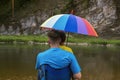 Father and son at beach with rainbow colored umbrella to hide from rain. Family spending time on nature Royalty Free Stock Photo