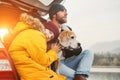 Father and son with beagle dog siting together in car trunk. Late autumn time