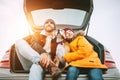 Father and son with beagle dog siting together in car trunk. Lon