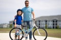 Father and son in bike helmet learning ride bicycle. Father and son on bicycle on summer day outdoor. Little son trying