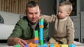 Father and son build tower using colorful wooden blocks Royalty Free Stock Photo