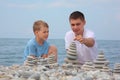 Father and son builds stone stacks on beach Royalty Free Stock Photo