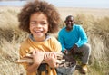 Father And Son Collecting Firewood On Beach