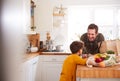 Father And Son Coming Home From Shopping Trip Using Plastic Free Bags Unpacking Groceries In Kitchen