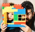 Father and son with concerned faces behind colorful bricks construction