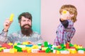 Father and son create constructions. Bearded man and son play together. Every dad and son must do together. Dad and kid