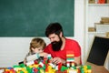 Father and son create toys from bricks. Dad and kid build of plastic blocks. Daddy takes part in game with little son Royalty Free Stock Photo