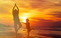 Father and son doing yoga at sunset sea Royalty Free Stock Photo