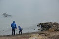 Father and son feed ducks on the river in winter